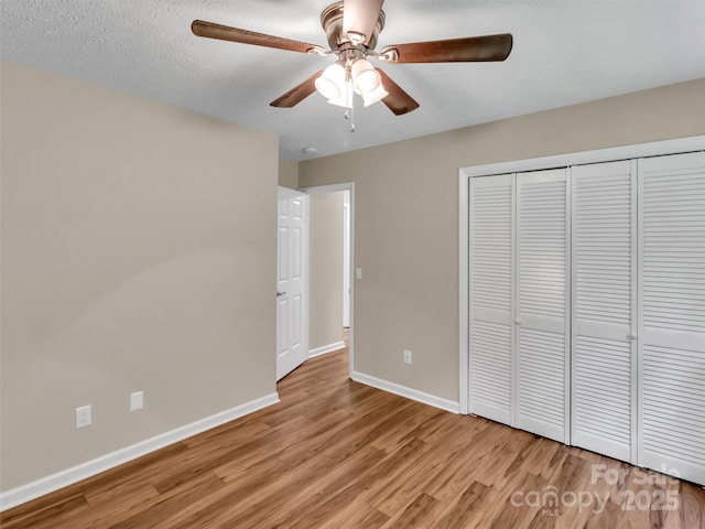 unfurnished bedroom featuring a textured ceiling, a closet, ceiling fan, and light wood-type flooring