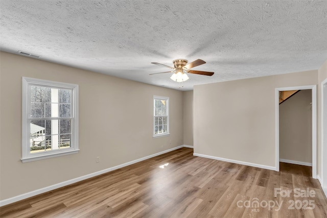 unfurnished room with a textured ceiling, light hardwood / wood-style floors, and ceiling fan