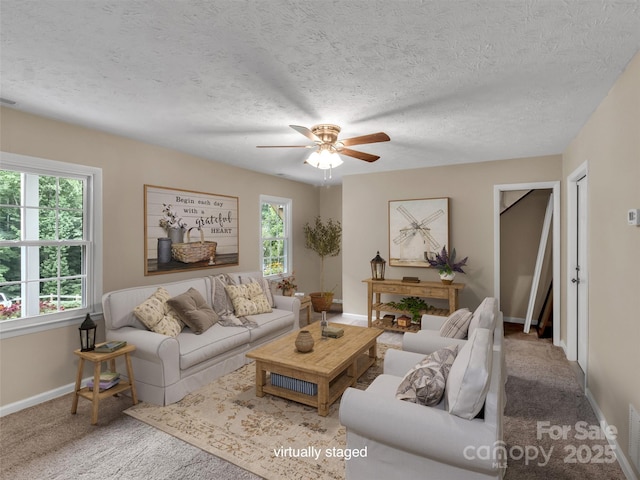 living room with ceiling fan, carpet flooring, and a textured ceiling