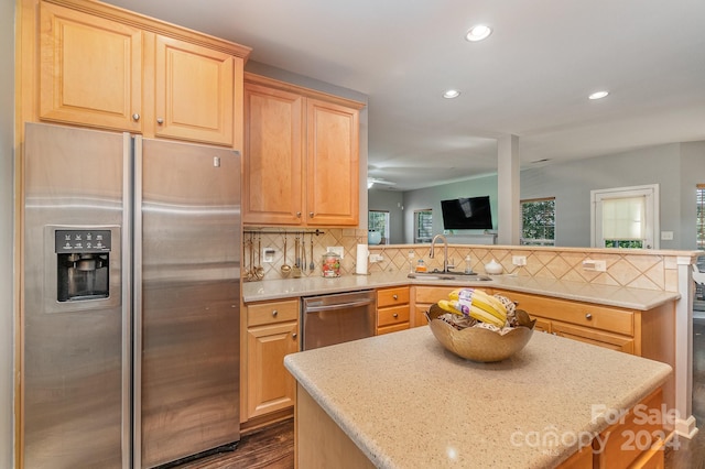 kitchen with tasteful backsplash, appliances with stainless steel finishes, sink, a kitchen island, and dark hardwood / wood-style flooring