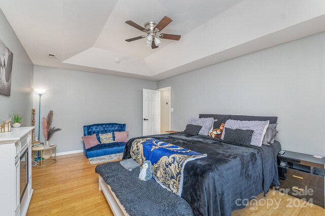 bedroom featuring hardwood / wood-style flooring, a tray ceiling, and ceiling fan