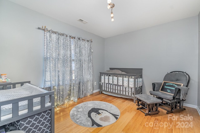 bedroom featuring hardwood / wood-style flooring and a crib