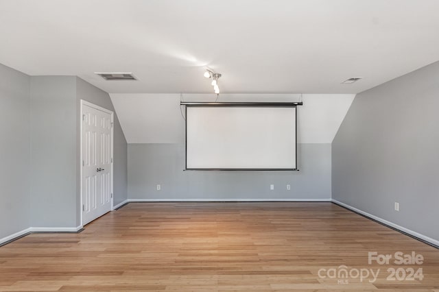 home theater room with lofted ceiling and light wood-type flooring