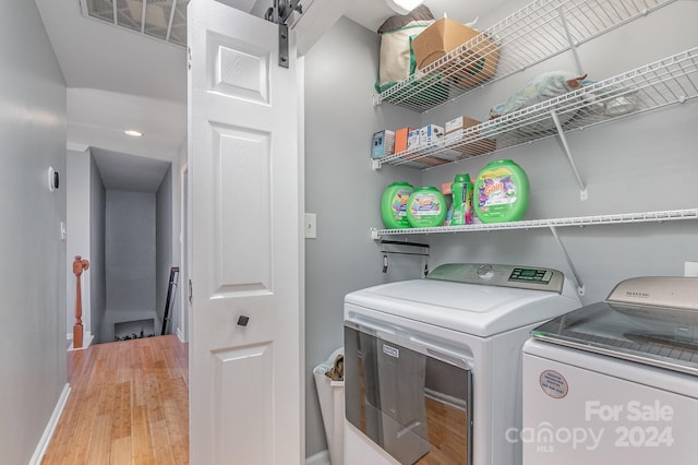 washroom with wood-type flooring and washing machine and dryer