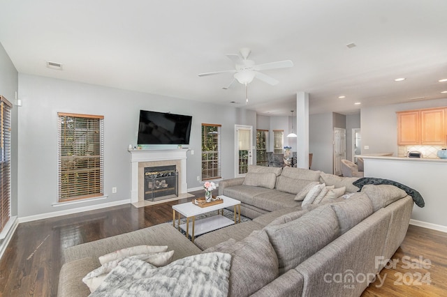 living room featuring dark hardwood / wood-style floors, a healthy amount of sunlight, a tiled fireplace, and ceiling fan