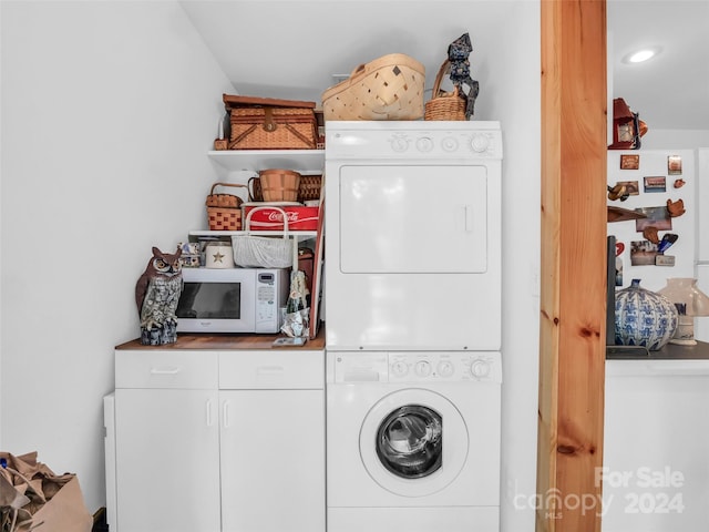 laundry room with cabinets and stacked washer and dryer