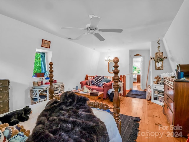 bedroom with ceiling fan with notable chandelier and light hardwood / wood-style floors