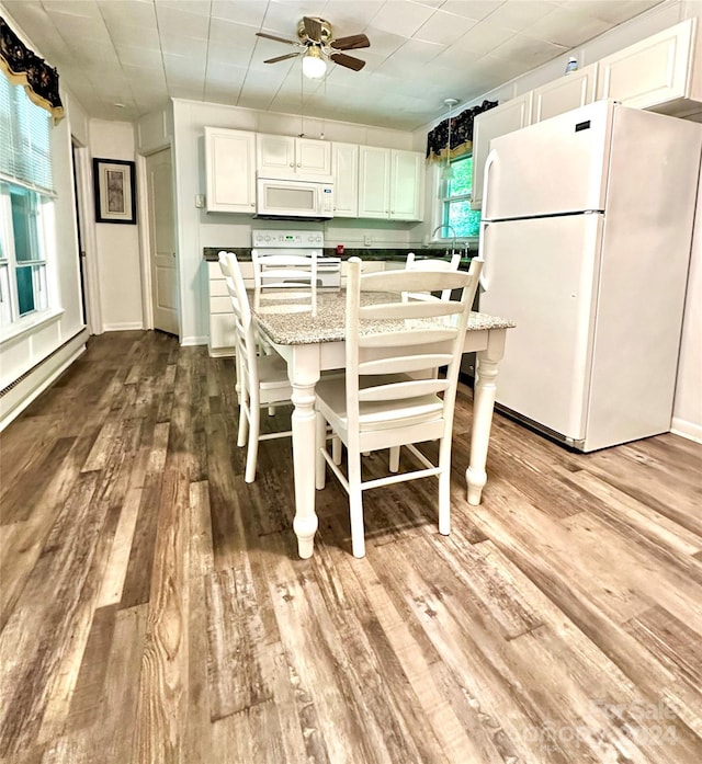 kitchen featuring light hardwood / wood-style floors, a breakfast bar, white appliances, light stone countertops, and white cabinets