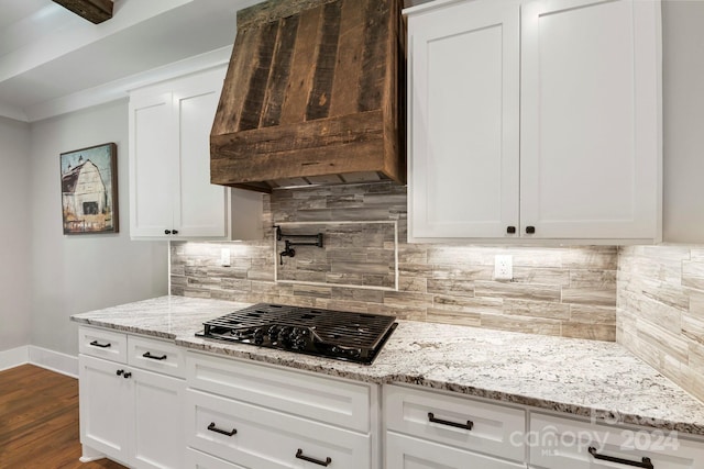 kitchen with tasteful backsplash, dark hardwood / wood-style flooring, white cabinetry, custom range hood, and black gas stovetop