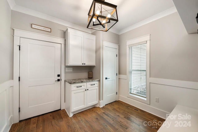 doorway with ornamental molding, an inviting chandelier, and dark hardwood / wood-style flooring