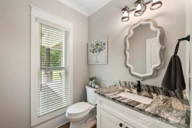 bathroom with toilet, ornamental molding, and vanity