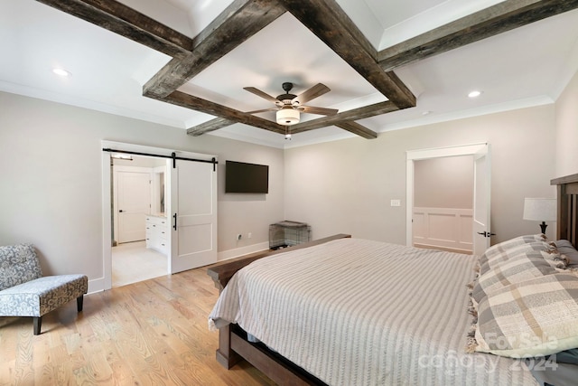 bedroom featuring ceiling fan, beamed ceiling, light hardwood / wood-style flooring, and a barn door