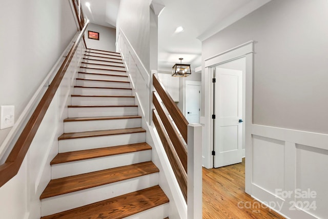 staircase with a chandelier and wood-type flooring