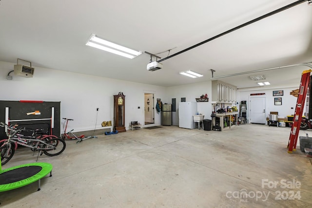 garage with a garage door opener, sink, white refrigerator, and stainless steel refrigerator