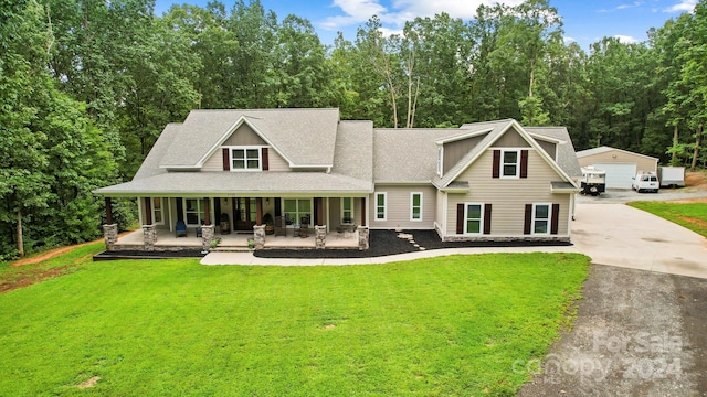 view of front facade with a porch, an outdoor structure, a front yard, and a garage