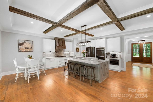 kitchen featuring white cabinetry, appliances with stainless steel finishes, a center island, and light wood-type flooring