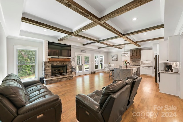 living room with beam ceiling, light hardwood / wood-style flooring, and a healthy amount of sunlight