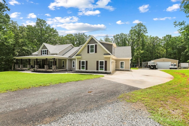 view of front of home with a front lawn, an outbuilding, a garage, and covered porch