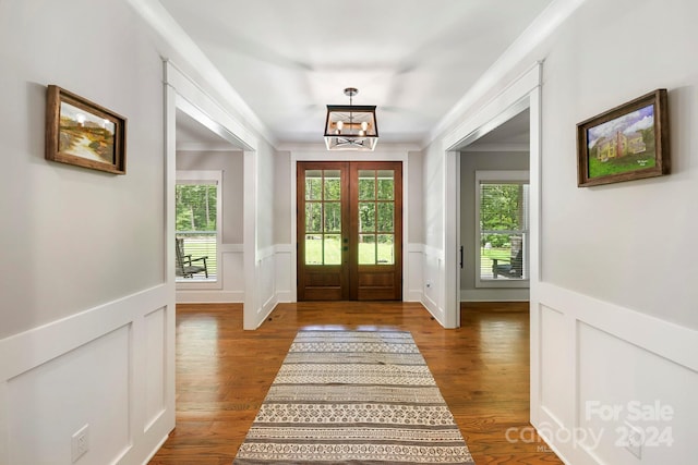 foyer entrance featuring french doors, crown molding, hardwood / wood-style flooring, and a notable chandelier