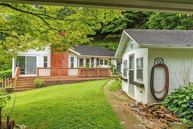 rear view of house featuring a shingled roof, a lawn, and a wooden deck