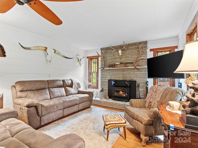 living room with a stone fireplace, light hardwood / wood-style floors, and ceiling fan