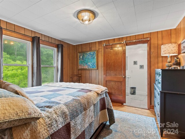 bedroom featuring light hardwood / wood-style flooring and wooden walls