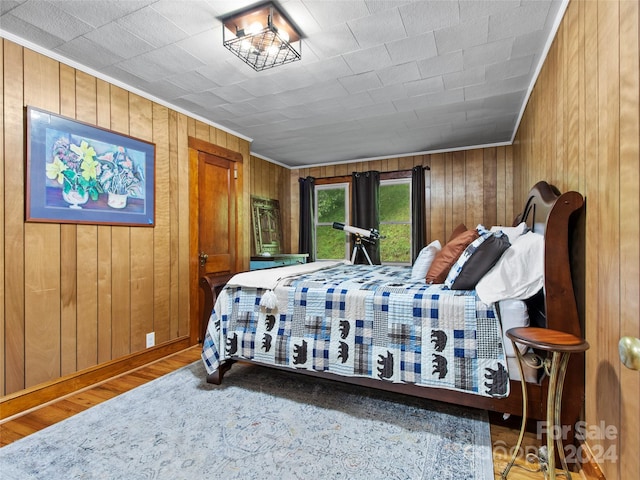 bedroom with wood walls, crown molding, and hardwood / wood-style floors