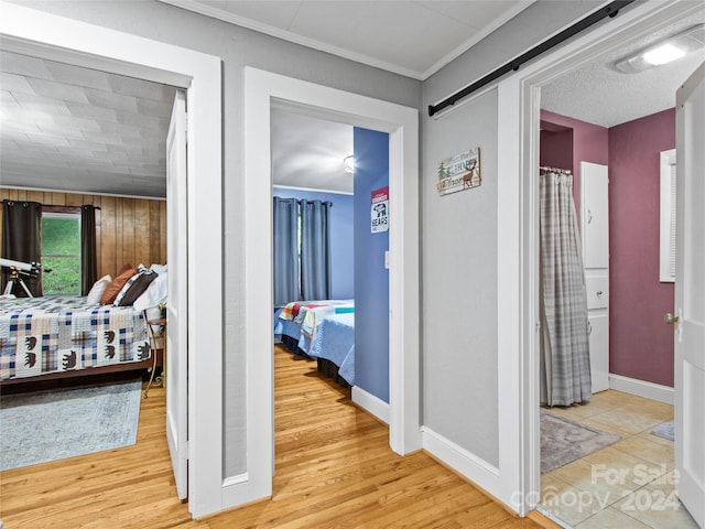 hall featuring ornamental molding, light wood-type flooring, baseboards, and a barn door