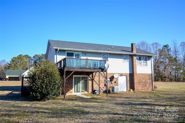 rear view of house with brick siding, a chimney, a lawn, central AC, and a deck