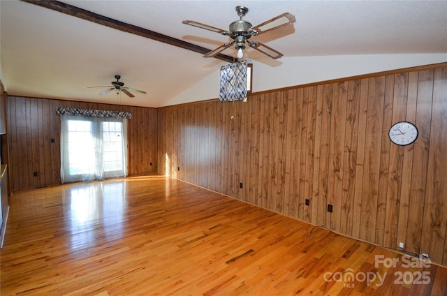 spare room with lofted ceiling, wood finished floors, and wooden walls