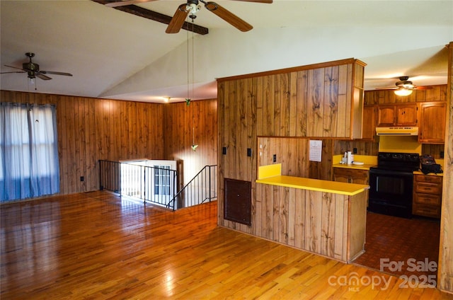 kitchen featuring wooden walls, brown cabinetry, black range with electric stovetop, wood finished floors, and range hood