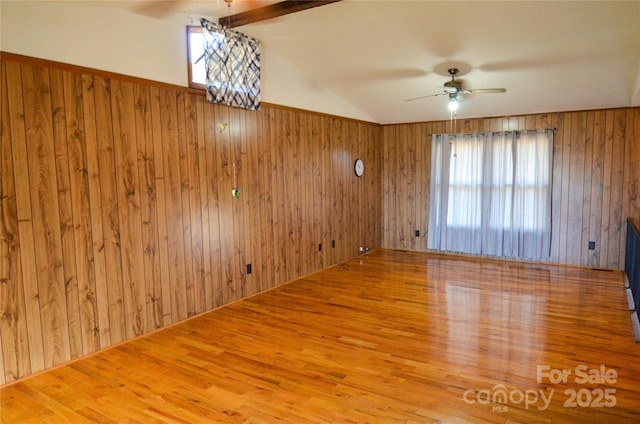 spare room with vaulted ceiling with beams, wood walls, ceiling fan, and wood finished floors