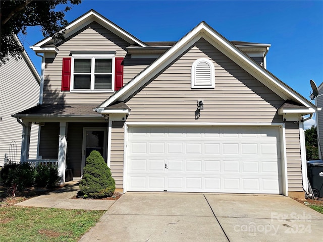 traditional-style home featuring a porch, an attached garage, and driveway