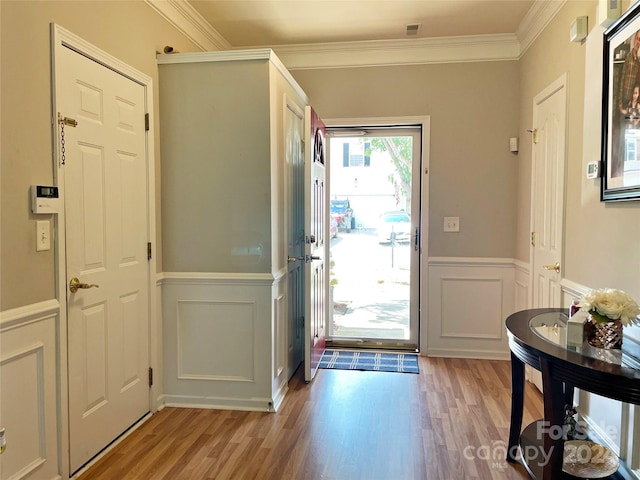 foyer entrance featuring crown molding and light wood-type flooring