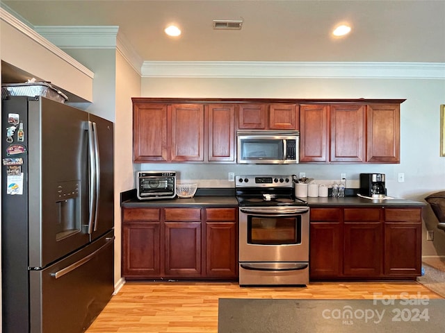 kitchen with visible vents, ornamental molding, dark countertops, light wood-style floors, and appliances with stainless steel finishes