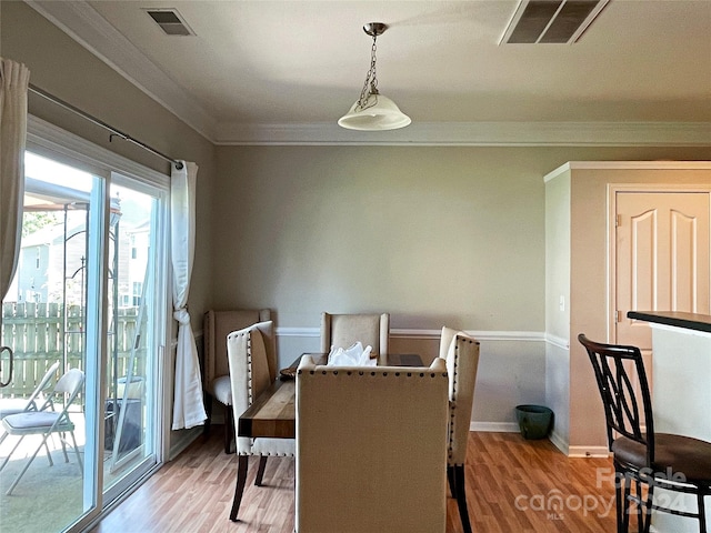 dining space featuring visible vents, wood finished floors, and crown molding