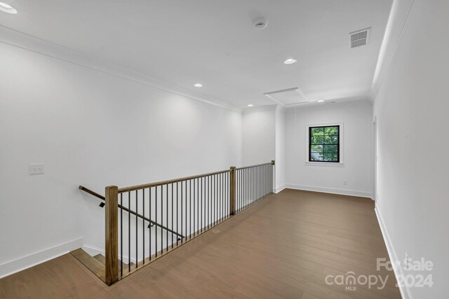 empty room featuring crown molding and wood-type flooring