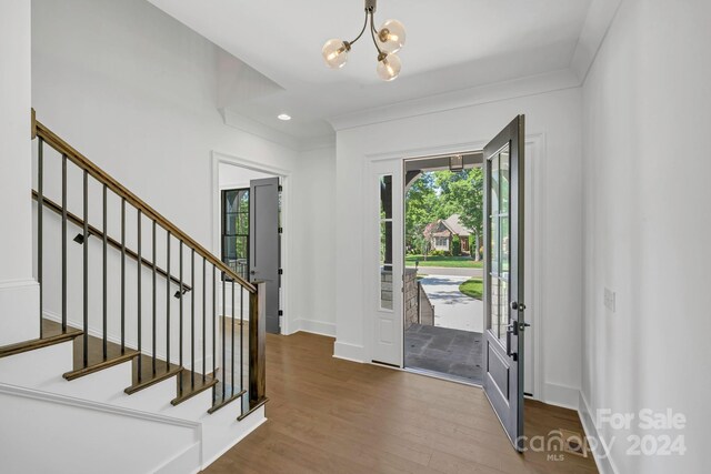 foyer featuring hardwood / wood-style floors, ornamental molding, and a chandelier