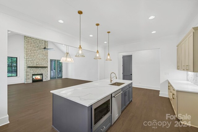 kitchen with a fireplace, dark hardwood / wood-style flooring, stainless steel appliances, sink, and cream cabinets