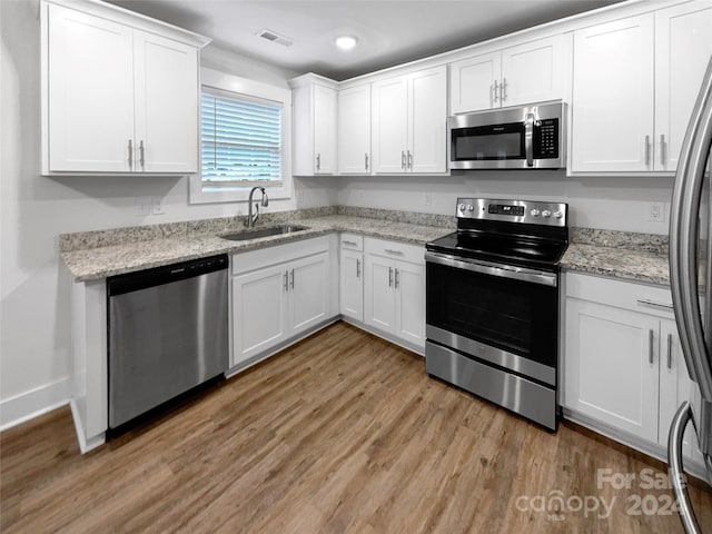 kitchen featuring appliances with stainless steel finishes, sink, light stone counters, and white cabinetry