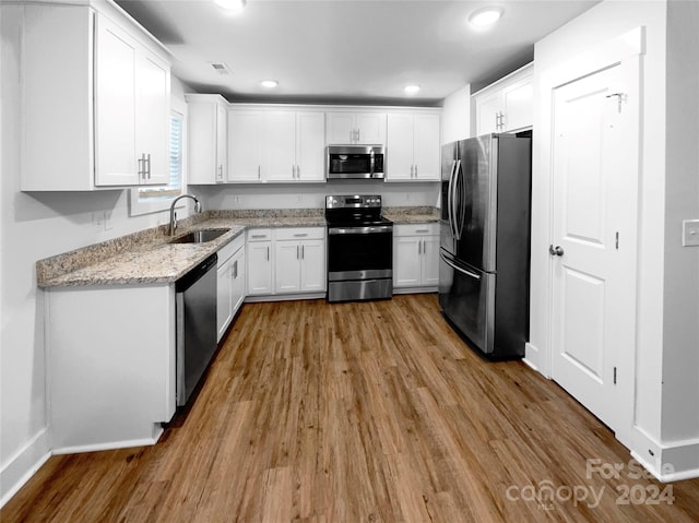 kitchen with white cabinetry, light hardwood / wood-style floors, stainless steel appliances, light stone countertops, and sink