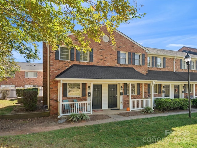 multi unit property featuring a porch and a front lawn