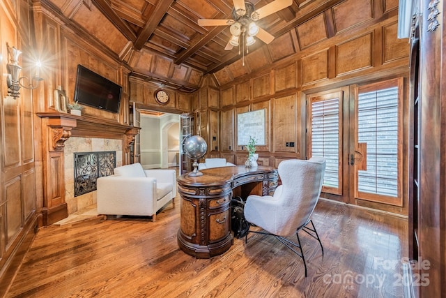 office featuring hardwood / wood-style floors, wood ceiling, a fireplace, ceiling fan, and beam ceiling