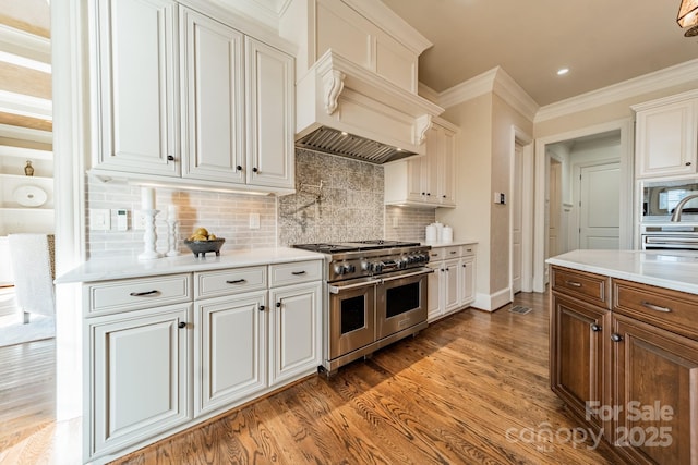 kitchen with backsplash, dark wood-type flooring, appliances with stainless steel finishes, ornamental molding, and white cabinets