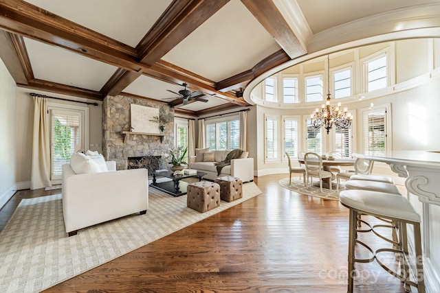 living room featuring ceiling fan with notable chandelier, beamed ceiling, a fireplace, light hardwood / wood-style flooring, and coffered ceiling