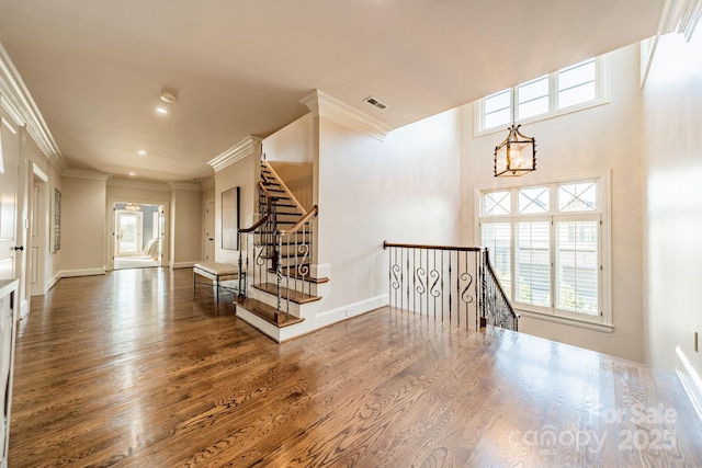 interior space with plenty of natural light, dark hardwood / wood-style floors, ornamental molding, and a notable chandelier