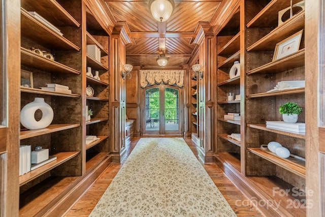 wine room with dark wood-type flooring, wood ceiling, and wooden walls