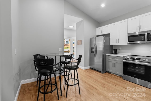 kitchen featuring white cabinets, stainless steel appliances, light hardwood / wood-style floors, vaulted ceiling, and gray cabinetry