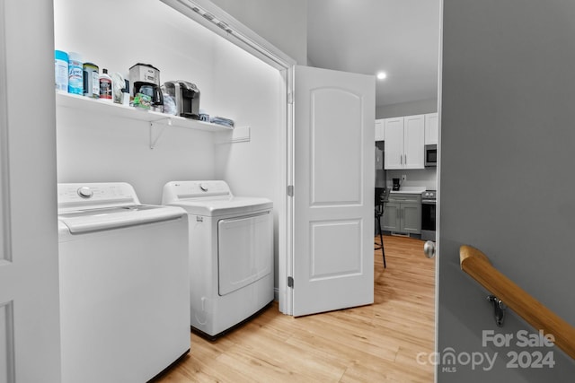 laundry area featuring washing machine and clothes dryer and light hardwood / wood-style flooring