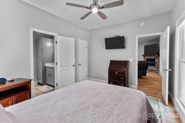 bedroom with light hardwood / wood-style flooring, ensuite bathroom, and ceiling fan